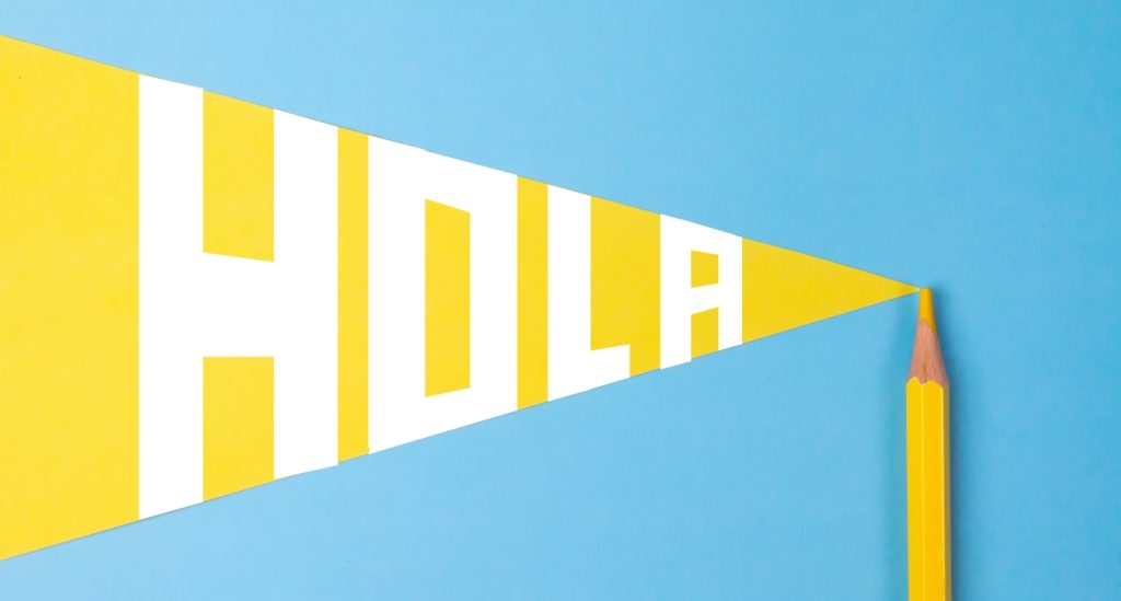 imagen con un lápiz amarillo y el texto "Hola" en mayúsculas